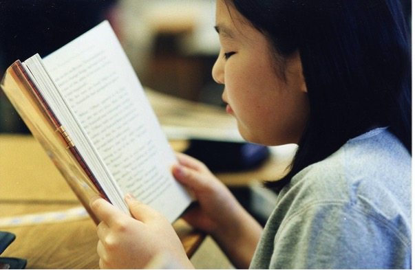 A young girl reading her book 