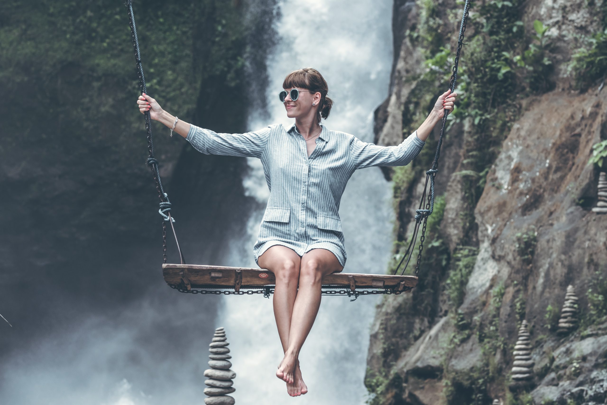 photo-of-woman-riding-swing-in-front-of-waterfalls